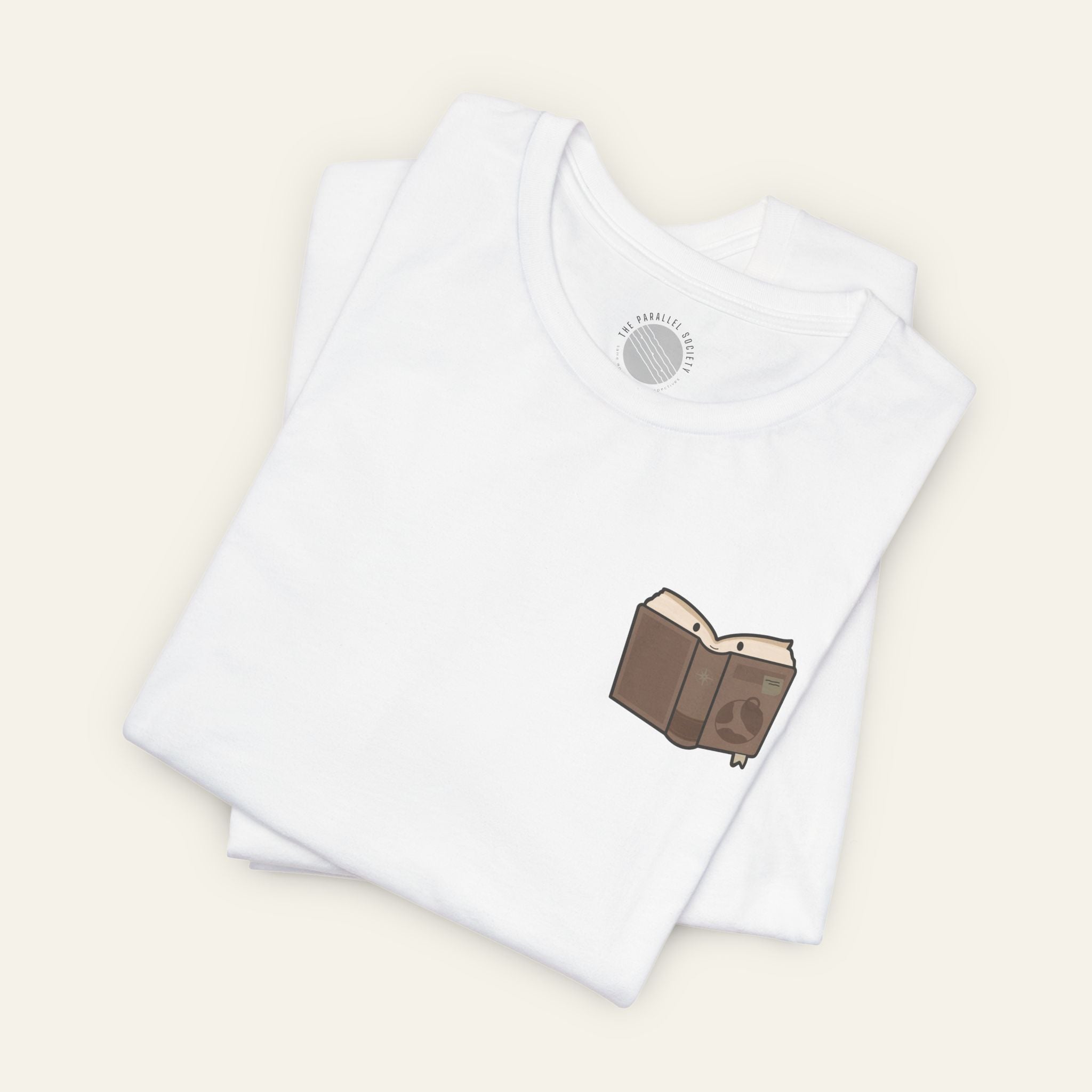 Folded white t-shirt with a open book character inspired by social navigation on a neutral background