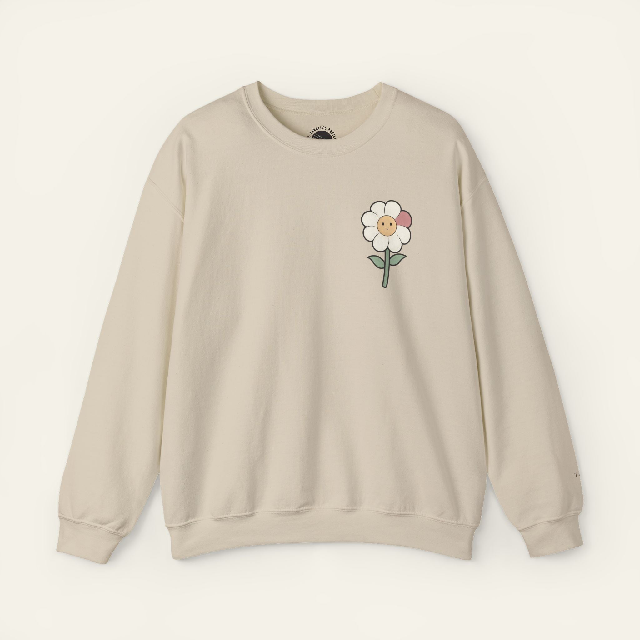 Sand sweatshirt with a flower character and mismatched petal inspired by visible growth on a neutral background